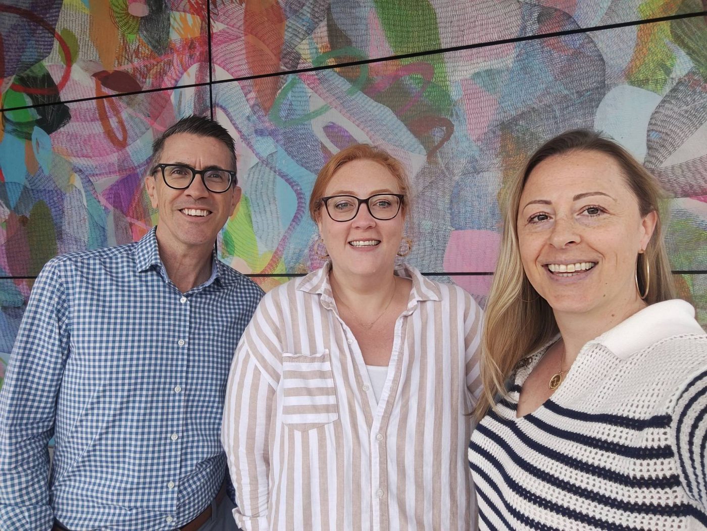 Applichat team members together in front of a colorful mural.